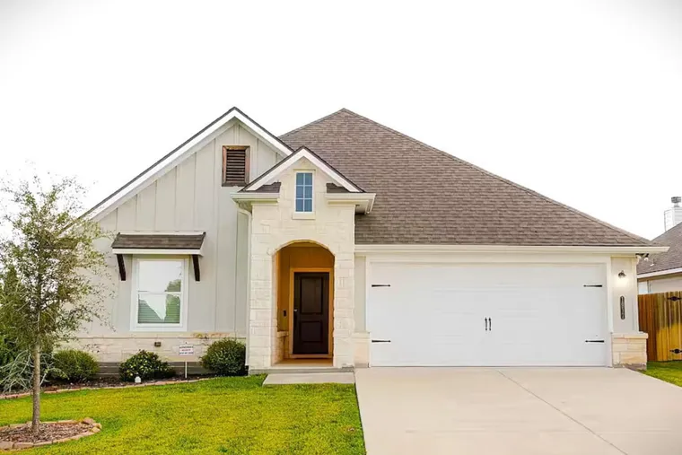 Single-storey stone and siding home with a manicured lawn