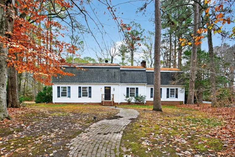 White clapboard cottage under autumn trees