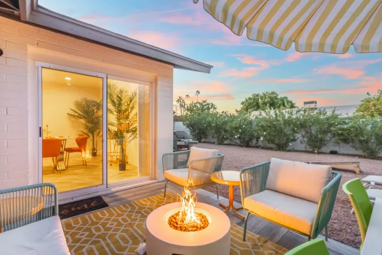 Desert patio with a lit firepit and lounge seating at sunset