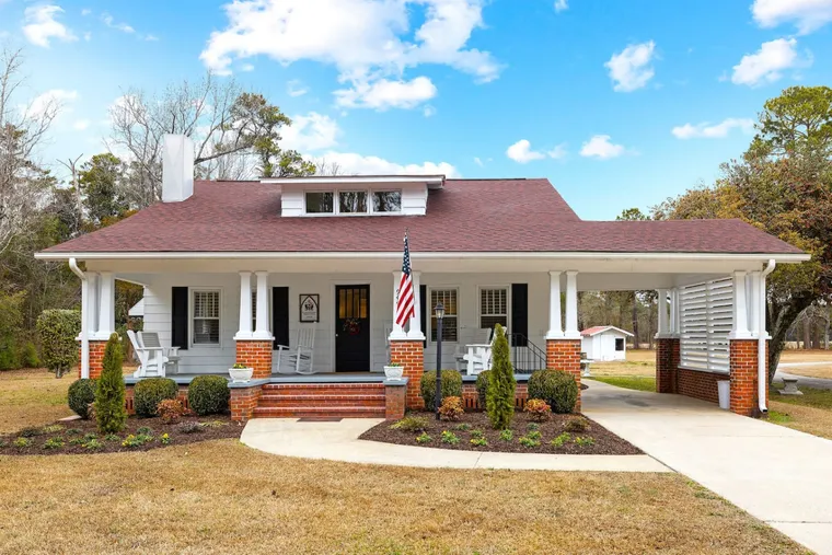 White bungalow with a red roof and a wide covered porch