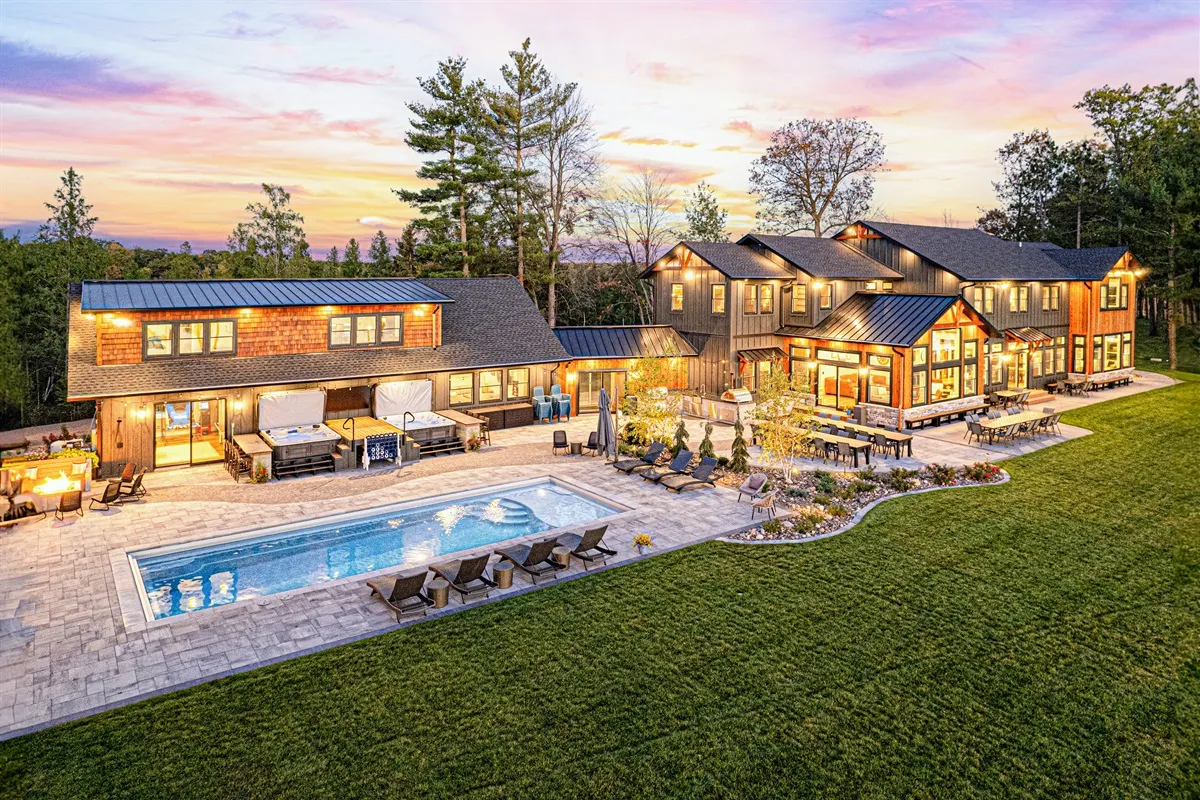Modern farmhouse estate with pool and outdoor dining at sunset