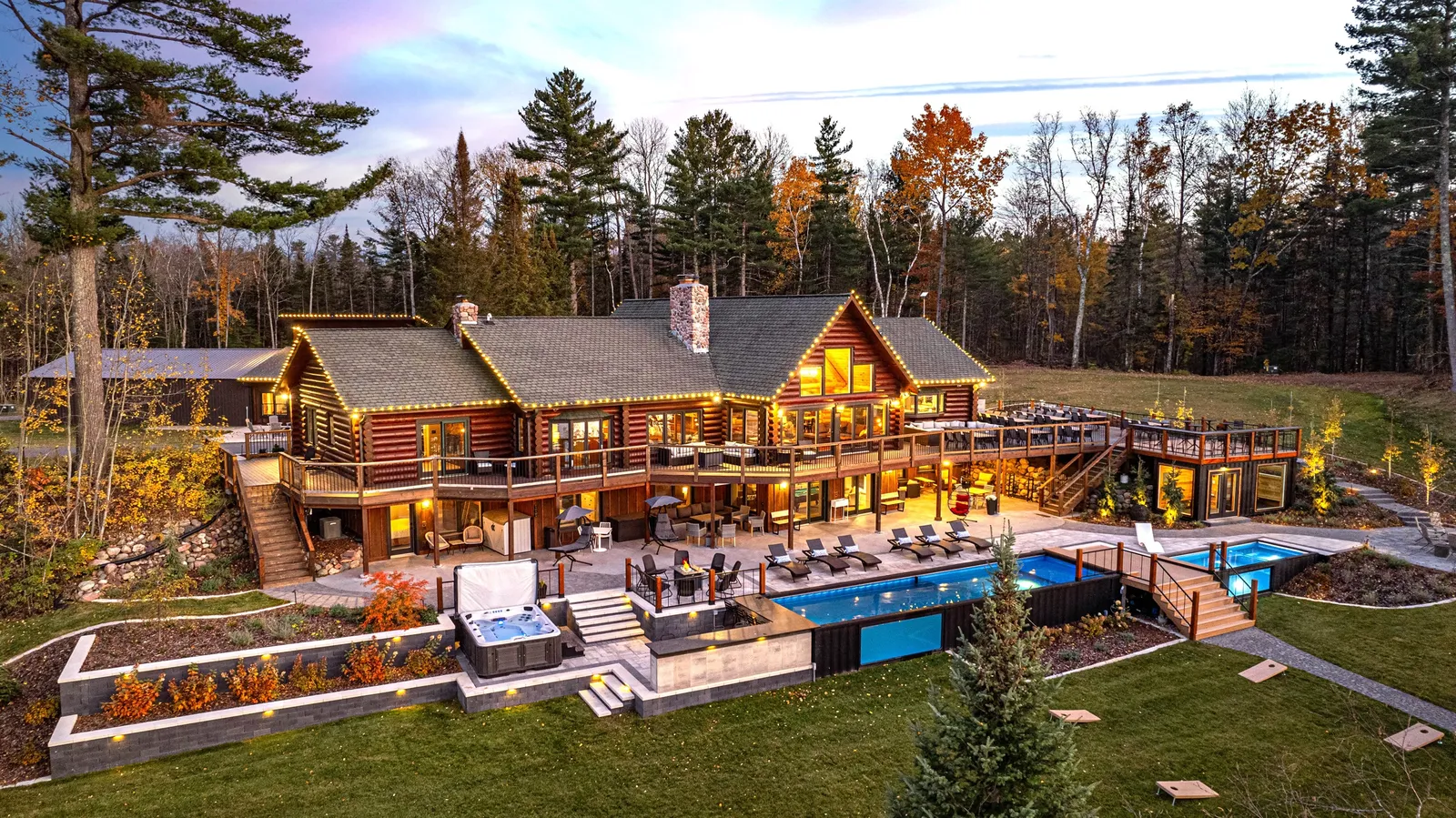 Estate-class log lodge with terraced pool decks at dusk